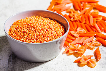 Raw red lentil pasta, gray background, close up. Vegan food concept.