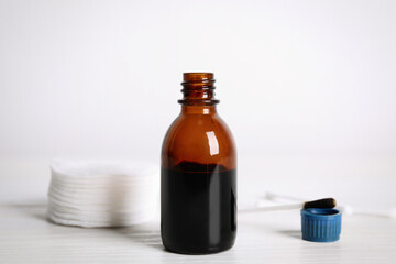 Bottle of medical iodine, cotton pads and buds on white wooden table