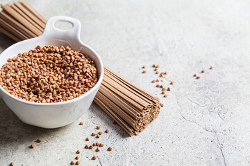 Raw soba - buckwheat noodles and buckwheat seeds in white bowl. Healthy food concept.