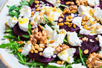 Baked beetroot salad with arugula, nuts and goat cheese, close up.