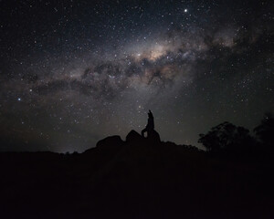 Silhouette of a Person Sitting on a Rock Watching the Milky way