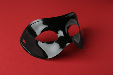 Black theatre mask on red background, closeup