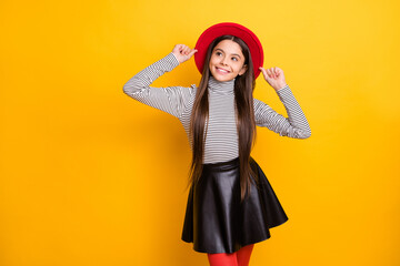 Portrait of attractive cheerful long-haired girl touching hat thinking creating idea isolated over bright yellow color background