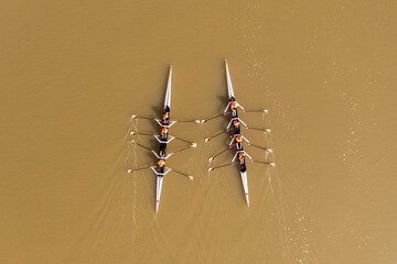 Two Sport Canoes with a team of four people racing on tranquil water, Aerial view.