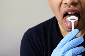 舌ブラシで舌を掃除する人物