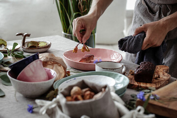Process of decorating rustic style table with craft plates, linen tablecloth and napkins , gluten free pastry and wild berries