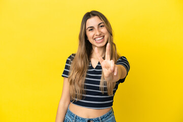 Young caucasian woman isolated on yellow background smiling and showing victory sign