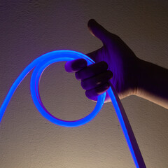 Flexible blue led tape neon in hand on black background