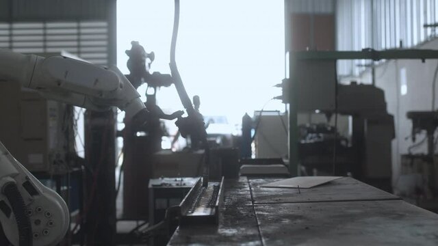 industrial 4.0 concept modern automated robot welding arm machine tool welds metal pipe and plate with bright sparks and smoke in production plant shop factort background