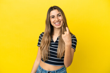 Young caucasian woman isolated on yellow background doing coming gesture