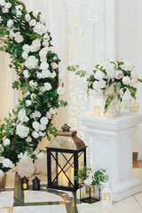 Elements of the wedding decoration and part of made of wedding round arch with white roses and greenery. 