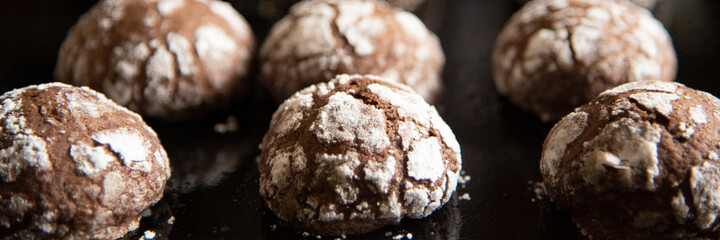 Cracked chocolate cookies with icing sugar on a pan