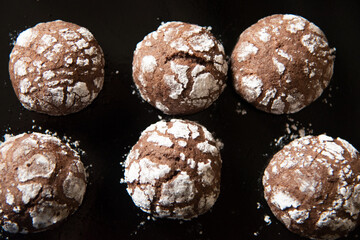 Cracked chocolate cookies with icing sugar on a pan