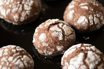 Cracked chocolate cookies with icing sugar on a pan
