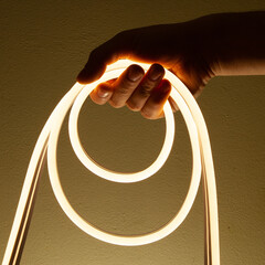 Flexible white led tape neon in hand on black background