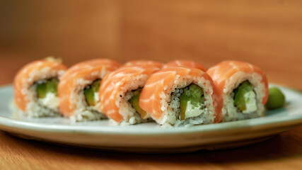 Closeup of set of Philadelphia sushi rolls with salmon, avocado, cream cheese on white plate