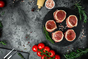 Raw Organic Fed Filet Mignon Steaks wrapped in bacon served on dark concrete background, Fresh pieces pork ready to cook, banner, menu recipe place for text, top view