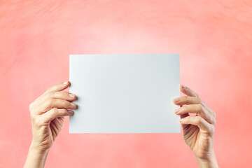 Mockup of female hands holding a colored cardboard on pink background