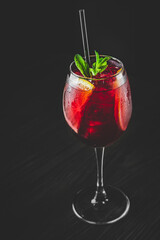 Cold sangria wine in a wine glass with reflection on black background