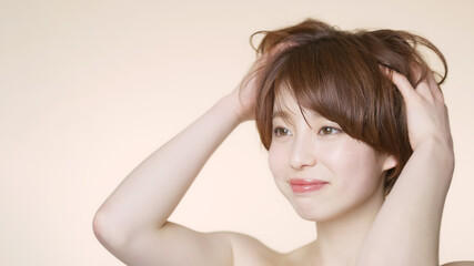 Fototapeta premium 髪をくしゃくしゃにするショートヘアの女性 ヘアケアイメージ 