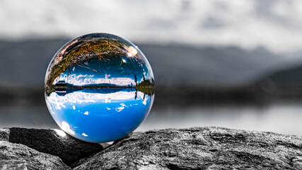 Crystal ball alpine landscape shot with black and white background outside the sphere at the famous Astberg summit, Going, Wilder Kaiser, Tyrol, Austria