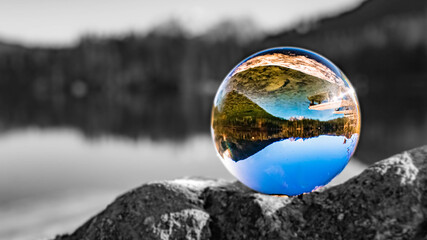 Crystal ball alpine landscape shot with black and white background outside the sphere at the famous Hintersee near Ramsau, Berchtesgaden, Bavaria, Germany
