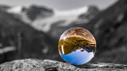 Crystal ball alpine landscape shot with black and white background outside the sphere at the famous Kaprun high mountain reservoirs, Salzburg, Austria