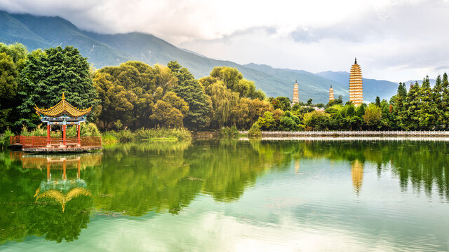 Scenic panorama of reflection park pond with the Three Pagodas and Cangshan mountains in background with dramatic light Dali Yunnan China