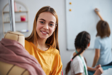 Cheerful girl using mannequin in sewing workshop