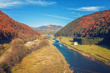 Aerial view of the mountain valley with the river and the small town of Kolochava on a sunny day. Mountain view in autumn. Beautiful natural landscape. Carpathian mountains. Ukraine