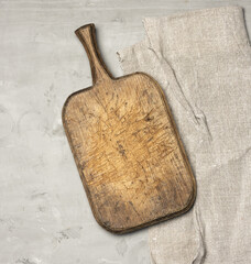 very old brown wooden kitchen cutting board and gray linen napkin on the table