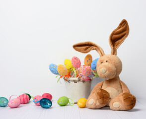 teddy bunny sitting on a white background and decorative colorful easter eggs