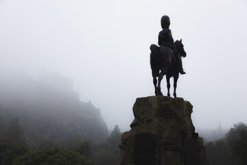 The Royal Scots Greys Monument, an ominous dark presence and equestrian statue over Princes Street Gardens on a misty, foggy day in Edinburgh, Scotland. - obrazy, fototapety, plakaty