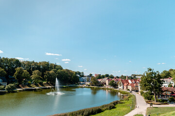 Beautiful fountain in the Lake of Talsi with old buildings on the side during sunny summer day