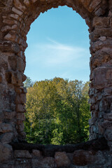 Window in the Koknese medieval castle ruins by the river Daugava with a beautiful and lush forest during sunny summer day