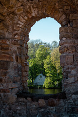 Window in the Koknese medieval castle ruins by the river Daugava with a beautiful and lush forest during sunny summer day
