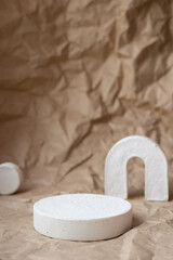 White cocncrete circle shaped pedestals on craft paper background. Podium mockup background for products. Advertising template. Stone platform. Abstract geometric pedestal.