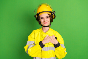 Photo of young woman firefighter happy positive smile hands on chest appreciate grateful isolated over green color background