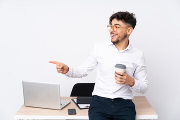 Arabian man in a office isolated on white background pointing finger to the side and presenting a product