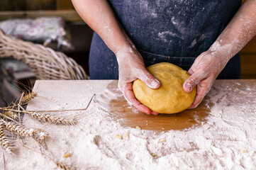 Female hands and dough. A woman is preparing a dough for home baking. Rustic style photo. Wooden table and flour. Free space for text