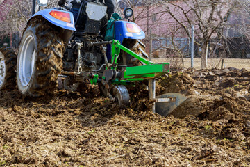 Farmer plows the field. Small tractor with a plow in the field. Cultivation.