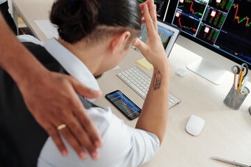 Trader supporting colleague monitoring stock market via application on smartphone