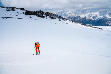 Fototapeta na wymiar man on skis climbs up the snow on a background of mountains