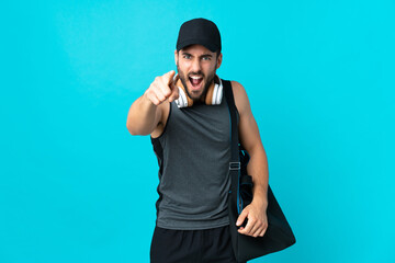 Fototapeta premium Young sport man with sport bag isolated on blue background frustrated and pointing to the front