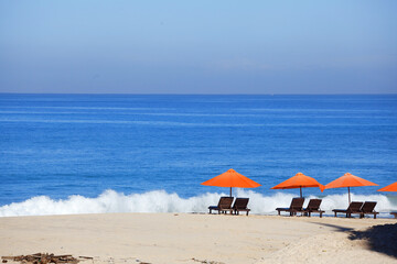empty beach background with bright tents, chairs, surf waves and sunny sky