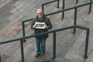 Obraz na płótnie Canvas Stop offense. Elderly protester holding a placard, demonstration. Human rights activist.