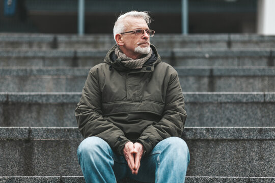 Lonely old man. A gray-haired man with wrinkles sits outside, sad. Lost a loved one, negative thoughts and depression.