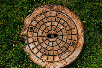 Rusty metal hatch texture. Against the background of green grass.