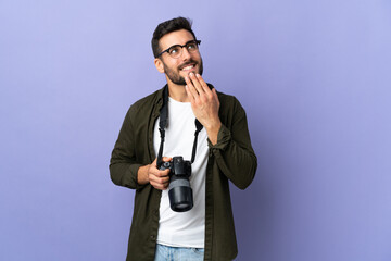 Photographer man over isolated purple background looking up while smiling