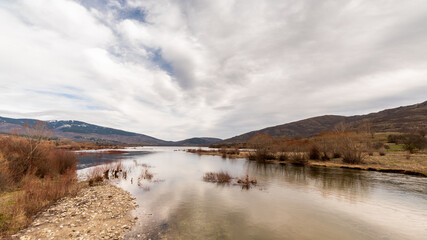 Landscape of mountains and reservoir with cloudy skies